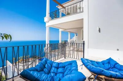 a balcony with blue couches and the ocean at Balancal Apartments and Villas Palheiro Village by Holiday Rental Madeira in Funchal