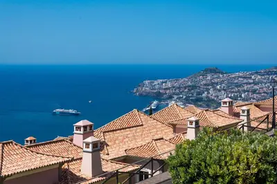 a view of roofs of houses and the ocean at Balancal Apartments and Villas Palheiro Village by Holiday Rental Madeira in Funchal