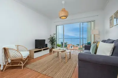 a living room with a blue couch and a tv at Ocean view Madeira in Caniço