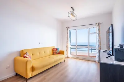 a living room with a yellow couch and a large window at Tucha's Apartement in Funchal