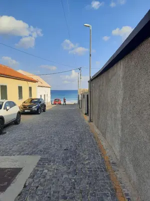 a cobblestone street with cars parked on the beach at Marear in Porto Santo