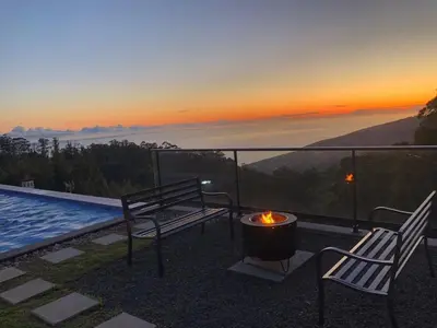 a patio with two chairs and a fire pit with the sunset at Casa da Arvore im Eukalyptuswald in Cova do Moirão