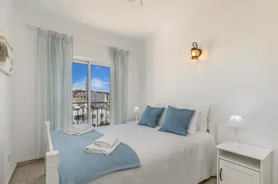 a white bedroom with a large bed and a window at Bela Vista Burgau in Burgau