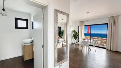 a bathroom with a mirror and a dining room with the ocean at Costa Vista by LovelyStay in Funchal
