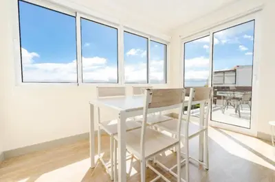 a white table and chairs in a room with windows at The Great Pearl Ocean Views Near Beach & Airport in Machico
