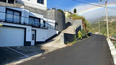 an empty street with a rainbow in the distance at Casa Gomes in Calheta