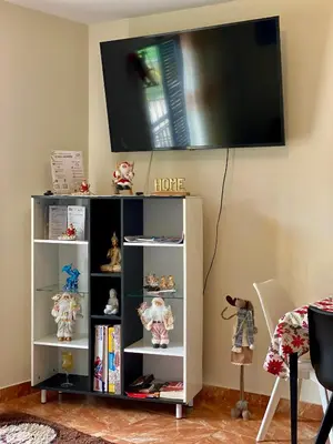 a tv on a wall above a book shelf at Casa Gomes in Calheta