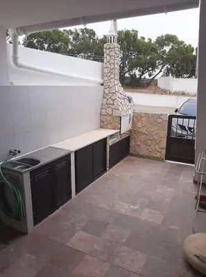 a patio with a stove and a stone wall at Amar Mar in Vila do Bispo