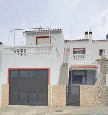 a white house with a black garage door at Amar Mar in Vila do Bispo