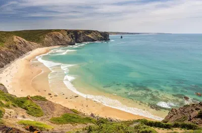 an aerial view of a beach with people in the water at Arrifana Sunset & Ocean View in Aljezur