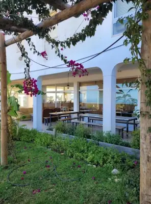 a building with a patio with tables and pink flowers at Arrifana Sunset & Ocean View in Aljezur
