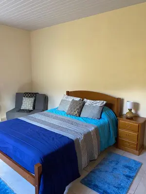 a bedroom with a bed with blue sheets and a blue rug at caminho da praia da maiata in Porto da Cruz