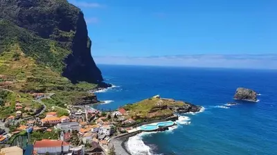 an aerial view of a village on a hill next to the ocean at caminho da praia da maiata in Porto da Cruz