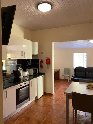 a kitchen with white cabinets and a table in a room at caminho da praia da maiata in Porto da Cruz