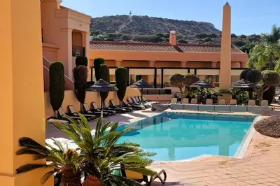 a swimming pool in front of a building with chairs at Luxury apartment at Baia da Luz in Luz