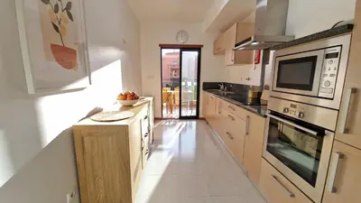 a kitchen with stainless steel appliances and wooden cabinets at Luxury apartment at Baia da Luz in Luz