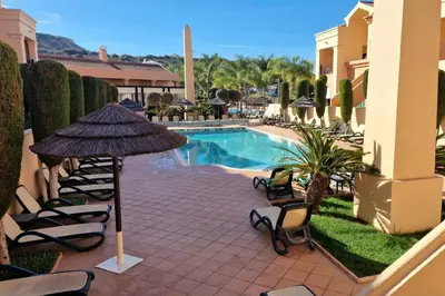 a patio with chairs and an umbrella and a pool at Luxury apartment at Baia da Luz in Luz