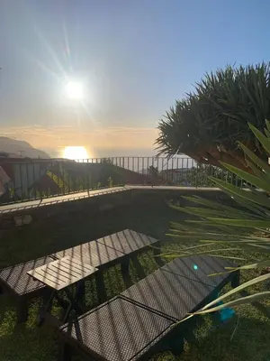 a table and benches in the grass with the sun at Namastê House II in Funchal