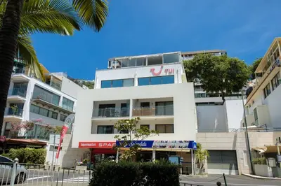 a tall white building with a palm tree in front of it at GuestReady - A sunny delight in Funchal in Funchal