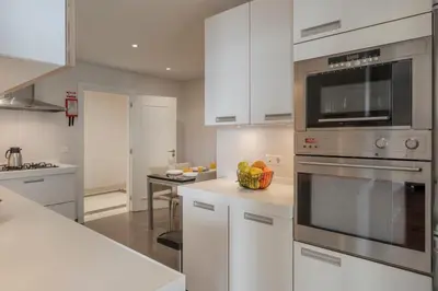 a kitchen with white cabinets and stainless steel appliances at Vila Formosa II by An Island Apart in Funchal