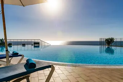 a large swimming pool with an umbrella and chairs at Vila Formosa II by An Island Apart in Funchal