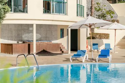 a swimming pool with two chairs and an umbrella at Vila Formosa II by An Island Apart in Funchal
