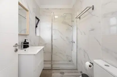 a white bathroom with a shower and a sink at TAC - Sagres Studio in Sagres
