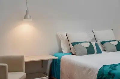 a room with two beds and a table and a chair at Pipas do Avô - Seixal by An Island Apart in Porto Moniz