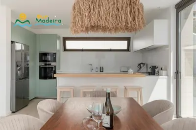 a kitchen and dining room with a wooden table with wine glasses at OurMadeira - Calheta Pearl in Estreito da Calheta