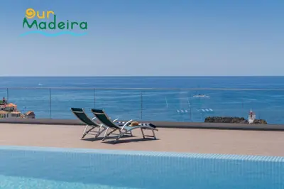 two chairs sitting next to a swimming pool at OurMadeira - Bayside in Câmara de Lobos