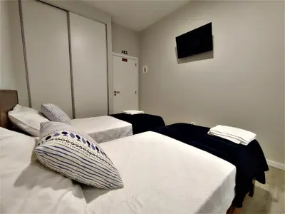 a hotel room with two beds and a flat screen tv at Funchal Apartments - New Botanic Garden Petit Studios in Funchal