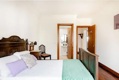 a bedroom with a large white bed with a wooden headboard at A ver o mar rooms- Funchal city center in Funchal