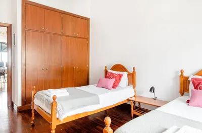a bedroom with two beds and a wooden cabinet at A ver o mar rooms- Funchal city center in Funchal