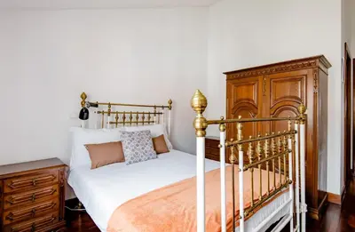 a bedroom with a bed and a wooden cabinet at A ver o mar rooms- Funchal city center in Funchal
