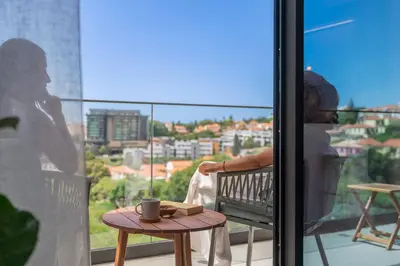 a person sitting on a balcony with a coffee cup on a table at Uptown 13 apartment by An Island Apart in Funchal