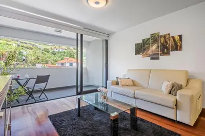 a living room with a couch and a glass table at EDU FLAT in Machico