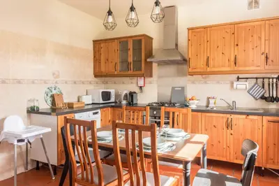 a kitchen with wooden cabinets and a table with chairs at Casa da Olides - T3 and Studio in Santana