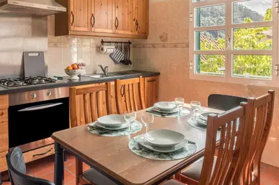 a kitchen with a wooden table with plates and wine glasses at Casa da Olides - T3 and Studio in Santana