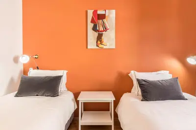 two beds in a room with an orange wall at Casa da Olides - T3 and Studio in Santana