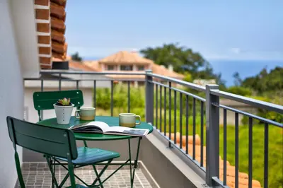 a table and chairs on a balcony with a book at Casa da Olides - Studio in Santana