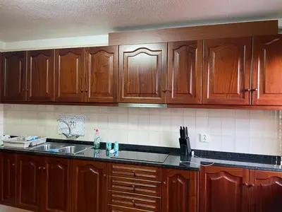 a kitchen with wooden cabinets and a sink at Casa da Isilda ,three bedrooms in Estreito da Calheta