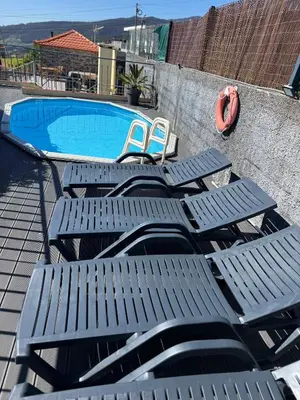 a table and two chairs sitting next to a stone wall at Casa do terno com piscina in Arco da Calheta