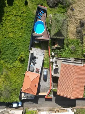 a stone house with red windows and a door at Casa do terno com piscina in Arco da Calheta