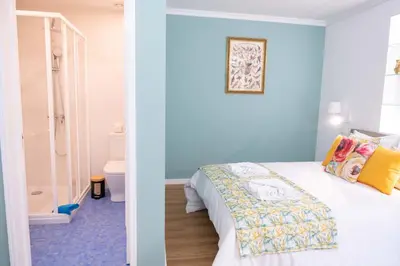 a bedroom with blue walls and a bed and a bathroom at D.Henrique I apartamento frente ao Savoy Palace in Funchal