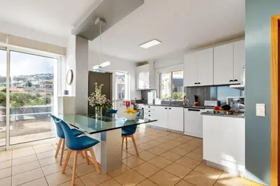 a kitchen with a glass table and blue chairs at Magnolia Sunsets in Calheta
