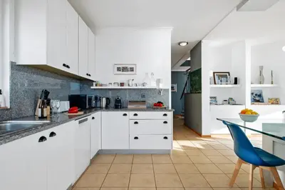 a kitchen with white cabinets and a blue chair at Magnolia Sunsets in Calheta