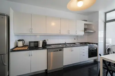 a white kitchen with white cabinets and a sink at Apartamento Princesa Dona Amélia by An Island Apart in Funchal