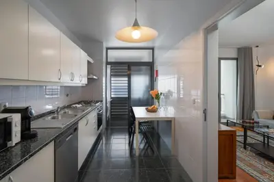 a kitchen with white cabinets and a table in it at Apartamento Princesa Dona Amélia by An Island Apart in Funchal
