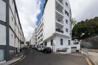 a white building with cars parked on the side of a street at Apartamento Princesa Dona Amélia by An Island Apart in Funchal