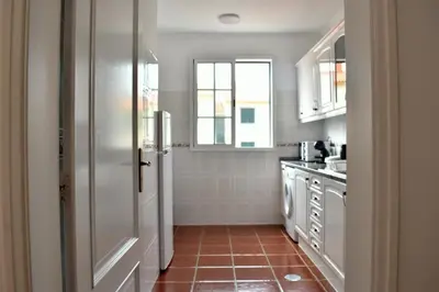 a kitchen with white cabinets and a red tile floor at Abrigo das Matas in Porto Santo